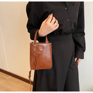 Détail d'un sac à main en cuir marron avec pendentif en cœur et logo métallique