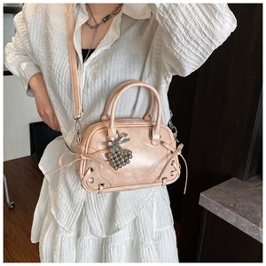 Detailansicht der eleganten rosa Umhängetasche mit Schleife und Herzanhänger-Deko