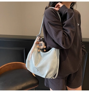 Détail d'un sac cabas en cuir souple bleu-argenté avec un charmant lion en peluche