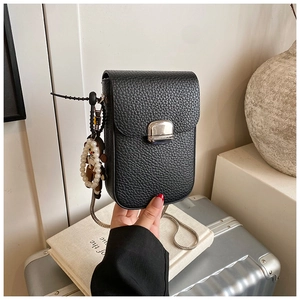 Close-up of black lychee leather phone bag with silver square buckle and pearl bear charm