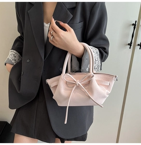 Détail du sac rose avec nœud montrant la texture grainée et la poignée élégante