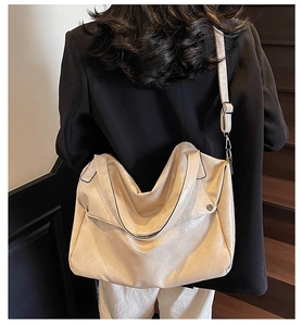 Detail showing high-capacity cream white soft leather tote bag with rivet metal accents