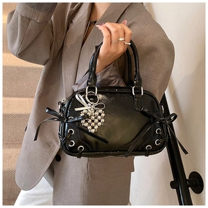 Detail der glänzenden schwarzen Boston Bag mit Schleifen und Herz-Perlenanhänger