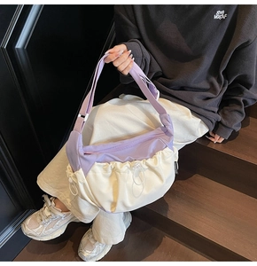 Detail view of contrast color crossbody bag with purple and white pleated nylon fabric