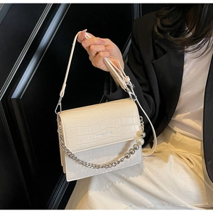 Detail of a beige croc-embossed handbag with pearl silver chain and leather shoulder strap