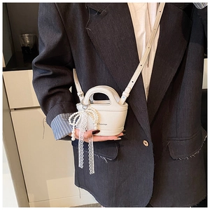 Close-up of white lychee texture mini bag with pearl chain and lace bow detail