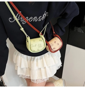 Détail du mini sac selle avec motif ours et fine bandoulière en cuir pour femme