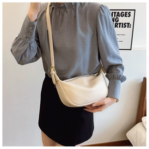 Close-up of off-white lychee leather texture and gold metal buckle on a crescent bag