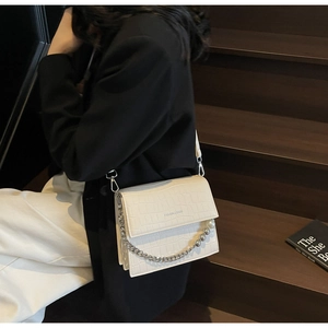 Detail of cream stone texture handbag with faux pearl and silver bead chain handle