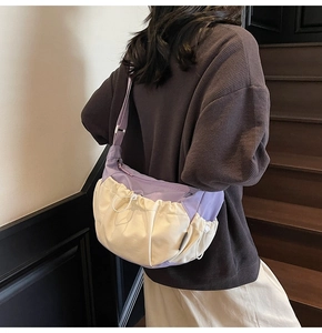 Detail of color-block casual crossbody bag with drawstring design shown on a model