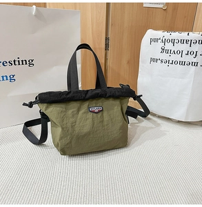 Detail of army green nylon crossbody bag with drawstring closure and logo patch