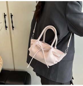 Détail du sac à main en cuir rose avec nœud papillon et finitions métalliques argentées