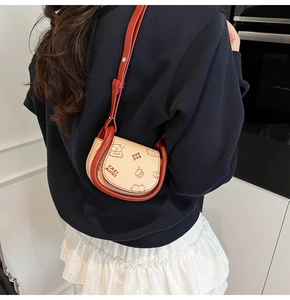 Détail du mini sac selle beige avec bordure rouge et motifs de cupcakes mignons