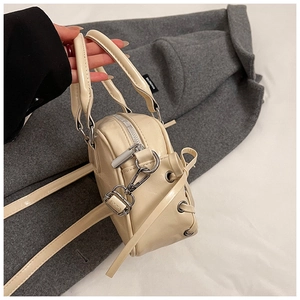 Detail der cremefarbenen Boston-Tasche mit Silberbeschlägen und seitlichem Schnürdesign