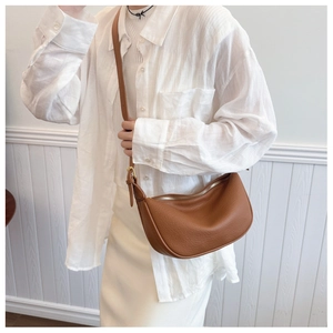 Close-up of brown litchi grain leather and gold zipper on a chic crescent bag