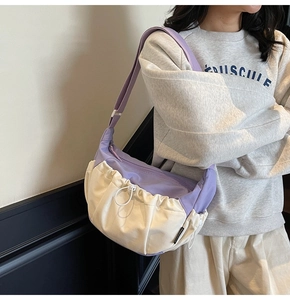Detail view of purple and beige sporty crossbody bag with drawstring pockets and wide strap