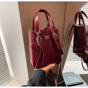 Détail de la texture cuir rouge vin brillant et du pendentif logo en forme de cœur