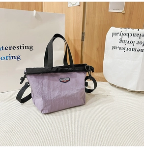 Close-up of lightweight nylon patchwork tote bag with brand label and adjustable strap