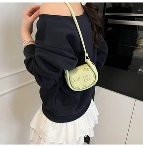 Détail du mini sac selle vert clair avec des motifs de dessins animés et fermoir magnétique