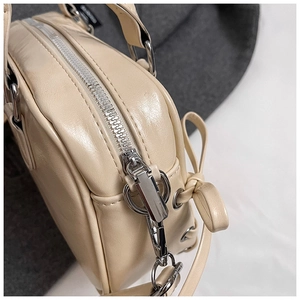 Detail der cremefarbenen Boston-Tasche mit Silber-Reißverschluss und Schleifendekor