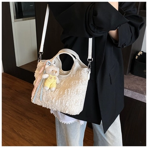 Détails de texture du sac seau plissé blanc avec breloque ours et poignée en cuir