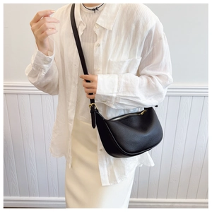 Detail of black pebbled leather half-moon bag with golden zipper and luxury texture