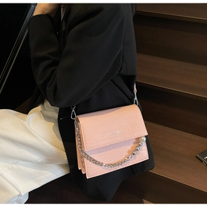 Detail of pink croc-embossed handbag with pearl metal chain strap and logo printing