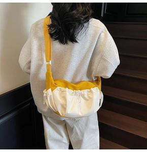 Detail of yellow and white canvas dumpling bag showing drawstring folds and adjustable strap