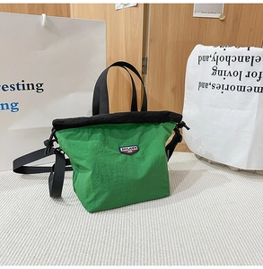 Detail of green nylon drawstring bag with adjustable strap and logo emblem on wood