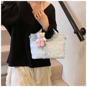 Détail de la texture jacquard du sac fourre-tout bleu clair avec breloque d'ours
