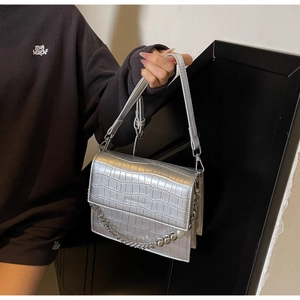 Detail of silver crocodile-embossed bag with pearl and metal chain decoration