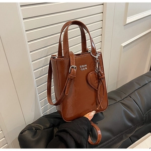 Sac bandoulière vintage en cuir huilé marron avec breloque cœur sur canapé noir