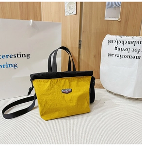 Detail view of yellow nylon tote bag featuring drawstring closure and brand label