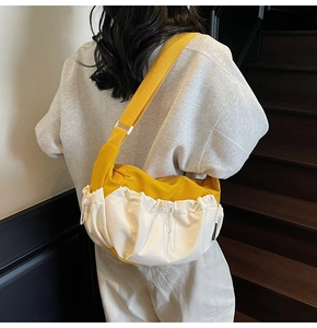 Detail of contrast color yellow and cream crossbody bag with drawstring pleats and wide strap