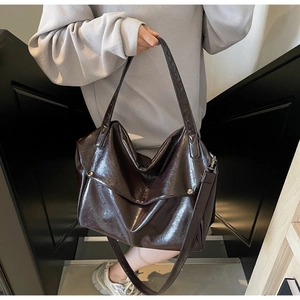 Macro detail of brown oil-wax leather tote bag with glossy finish and metal rivets