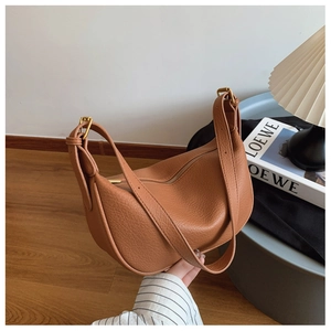 Detail of caramel lychee grain leather tote with adjustable strap and gold metal buckle