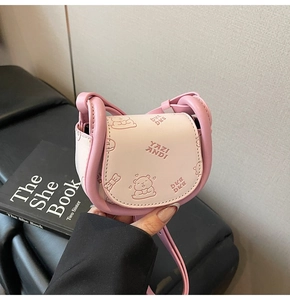 Détail du mini sac selle rose et beige avec ours en relief et motifs de donuts