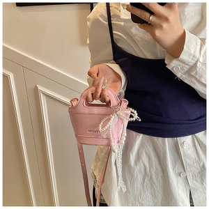 Pink mini handbag with pearl bow charm and detachable strap in a mirror selfie