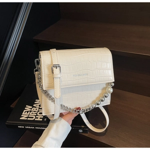 Close-up of white croc-embossed bag with pearl and silver bead metal chain details