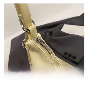 Détail macro du zip argenté et de la boucle en D sur un sac cabas en cuir jaune
