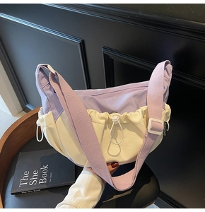 Detail shot of two-tone purple and beige crossbody bag with adjustable strap and drawstring