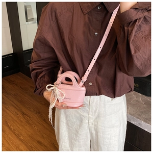 Pink mini leather crossbody bag featuring pearl lace bow and slim shoulder strap