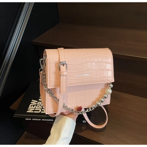 Detailed view of pink faux crocodile leather bag with pearl chain and fashion logo