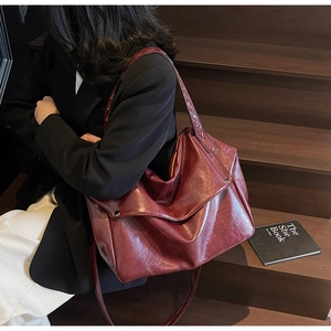 Macro detail of deep wine red oil wax leather tote bag showing soft texture and metal buckle