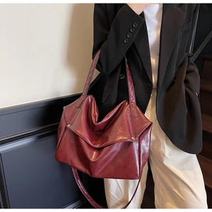Macro view of vintage burgundy oil wax leather tote bag with metallic buckle detail