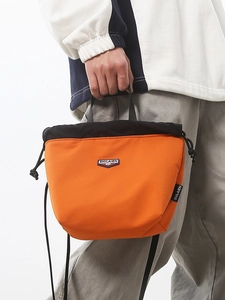Orange and black nylon drawstring crossbody bag with durable top handles and logo patch
