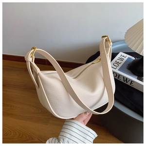 Detailed view of cream leather tote bag with pebble grain texture and gold hardware