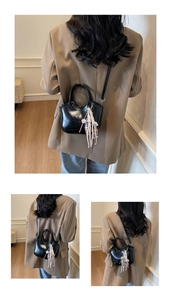 Detalle del bolso de cuero negro brillante con un elegante colgante de borla rosa y blanco