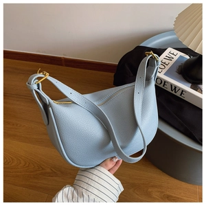 Detail of light blue lychee pattern leather shoulder bag with elegant gold hardware