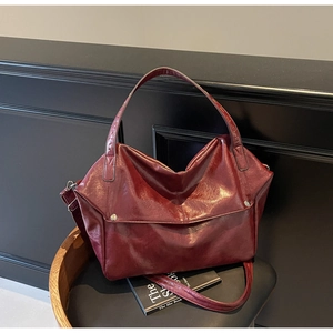 Macro detail of dark red oil wax leather tote bag with glossy finish and silver studs